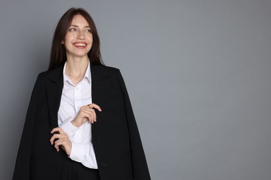 Photo of Happy woman in suit on grey background, space for text