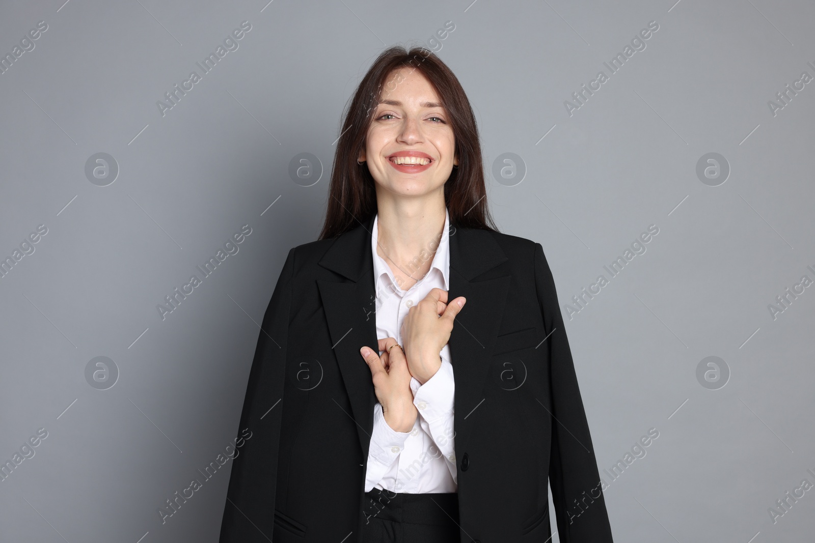 Photo of Happy woman in suit on grey background