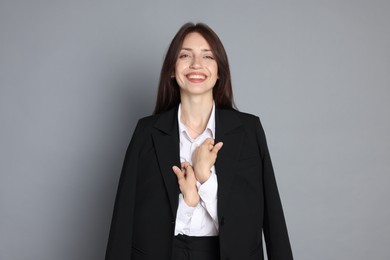 Photo of Happy woman in suit on grey background
