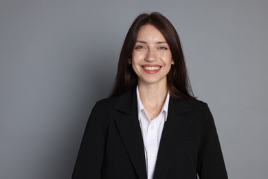 Photo of Happy woman in suit on grey background, space for text
