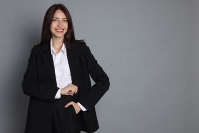 Photo of Happy woman in suit on grey background, space for text