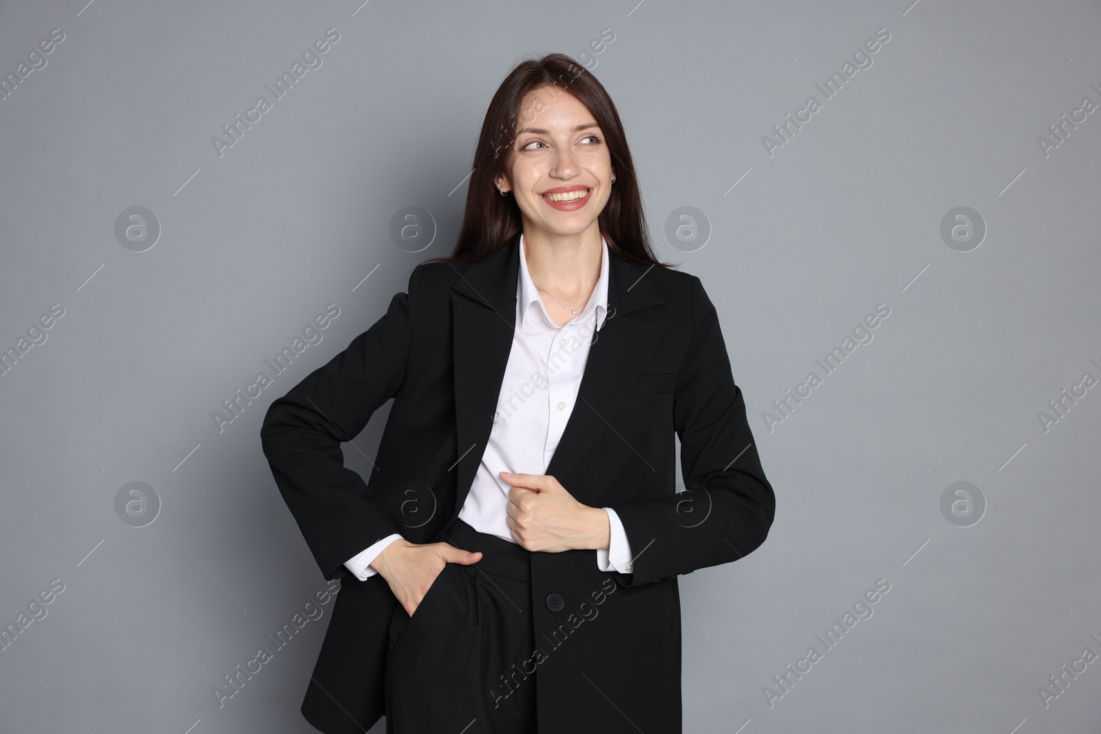 Photo of Happy woman in suit on grey background