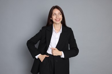 Photo of Happy woman in suit on grey background