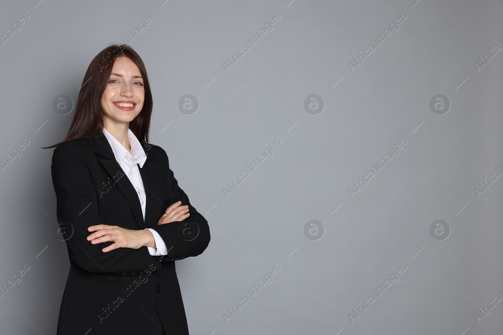 Photo of Happy woman in suit on grey background, space for text
