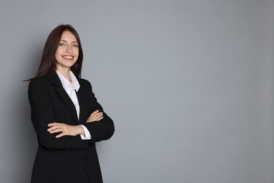 Photo of Happy woman in suit on grey background, space for text