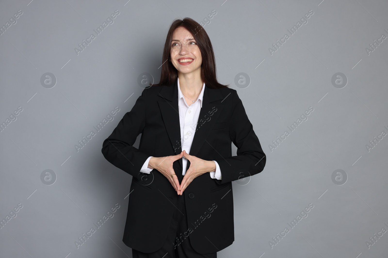 Photo of Happy woman in suit on grey background