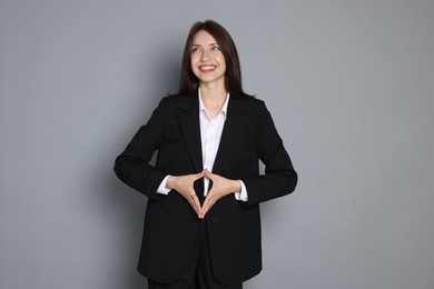 Photo of Happy woman in suit on grey background