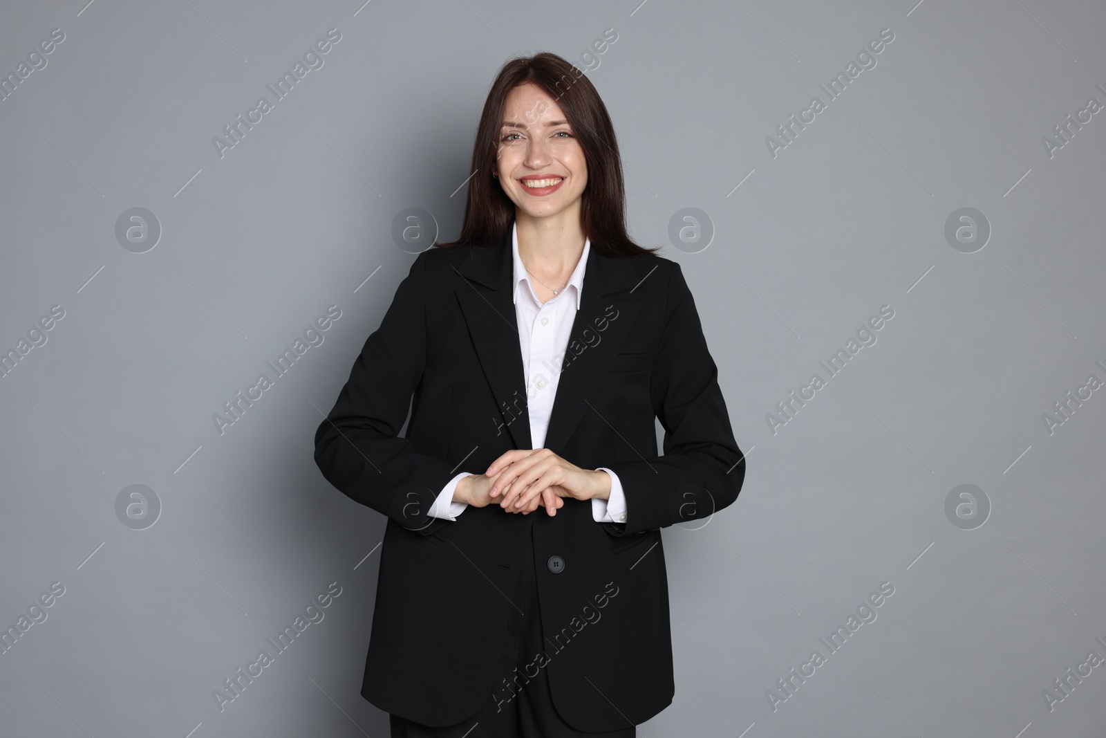 Photo of Happy woman in suit on grey background