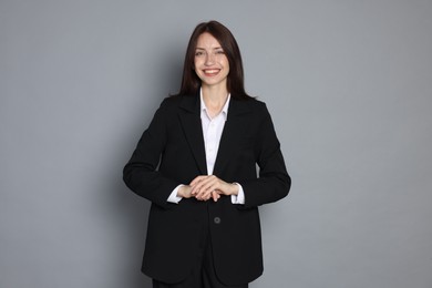 Photo of Happy woman in suit on grey background
