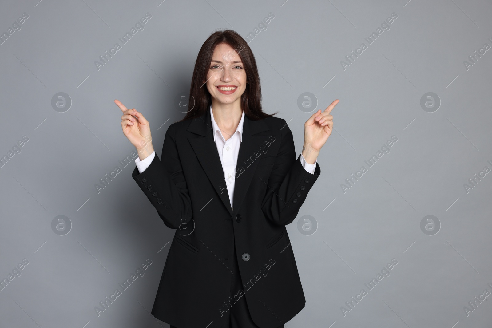 Happy woman in suit on grey background Photo of Happy woman in suit on grey background