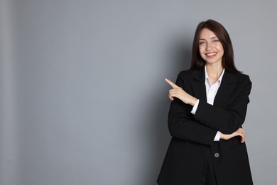 Photo of Happy woman in suit on grey background, space for text