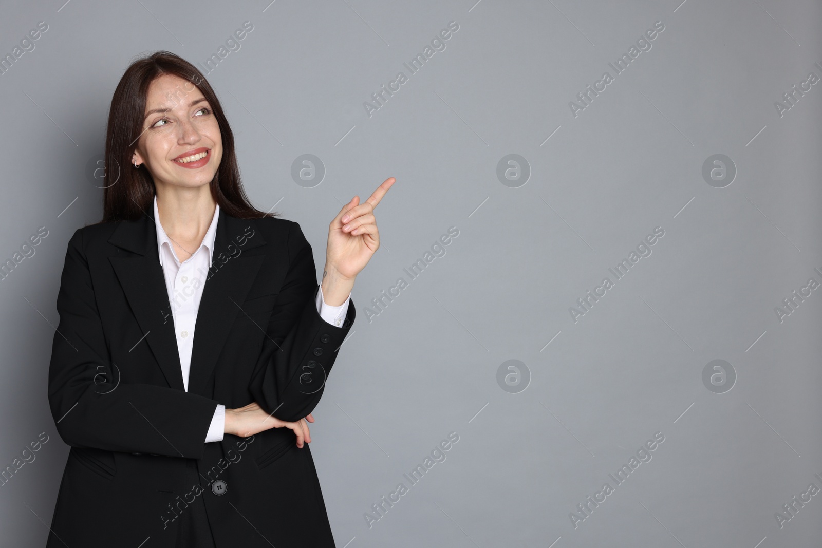 Photo of Happy woman in suit on grey background, space for text