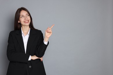 Photo of Happy woman in suit on grey background, space for text