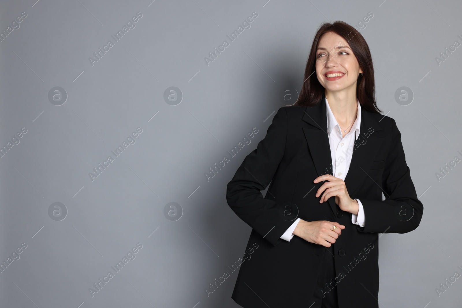 Photo of Happy woman in suit on grey background, space for text
