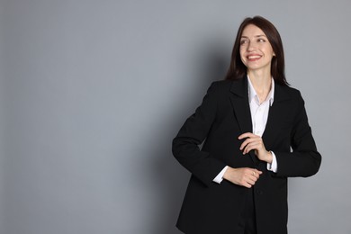 Photo of Happy woman in suit on grey background, space for text