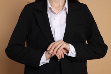Photo of Woman in suit on beige background, closeup