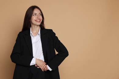 Photo of Happy woman in suit on beige background, space for text