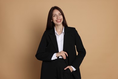 Photo of Happy woman in suit on beige background