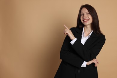 Photo of Happy woman in suit on beige background, space for text