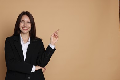 Photo of Happy woman in suit on beige background, space for text