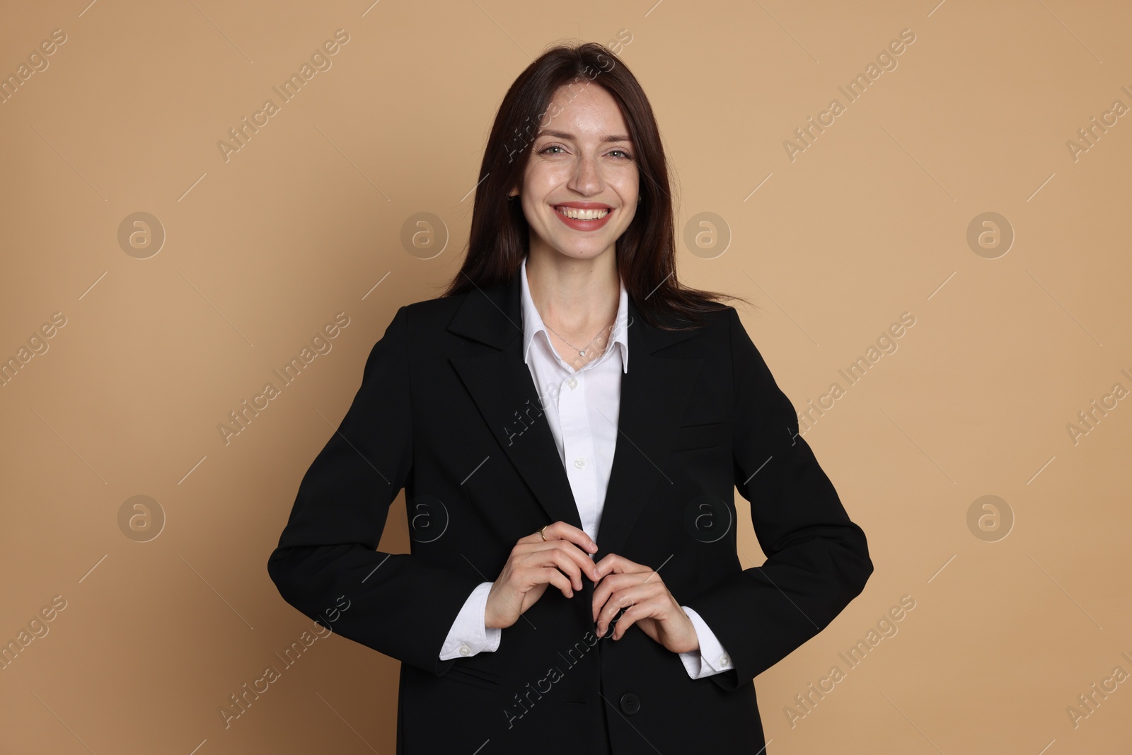 Happy woman in suit on beige background Photo of Happy woman in suit on beige background
