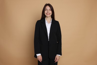 Photo of Happy woman in suit on beige background
