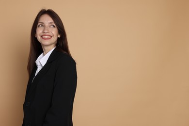 Photo of Happy woman in suit on beige background, space for text