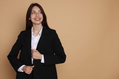 Photo of Happy woman in suit on beige background, space for text