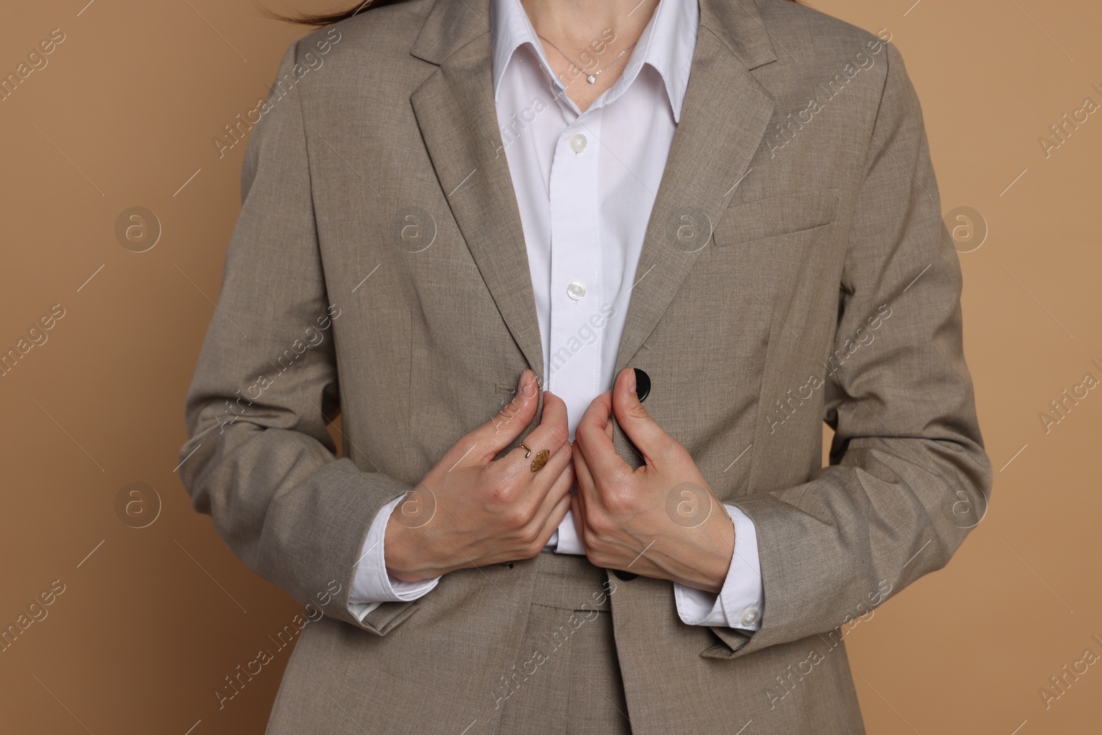 Woman in suit on beige background, closeup Photo of Woman in suit on beige background, closeup