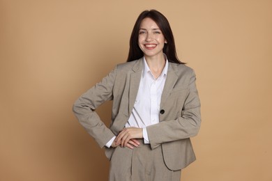 Photo of Happy woman in suit on beige background