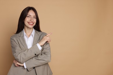 Photo of Happy woman in suit on beige background, space for text