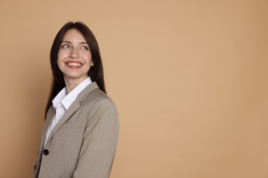Photo of Happy woman in suit on beige background, space for text