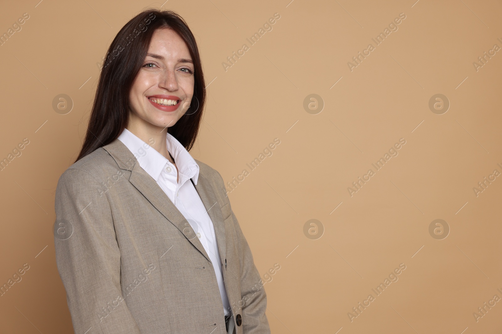 Photo of Happy woman in suit on beige background, space for text