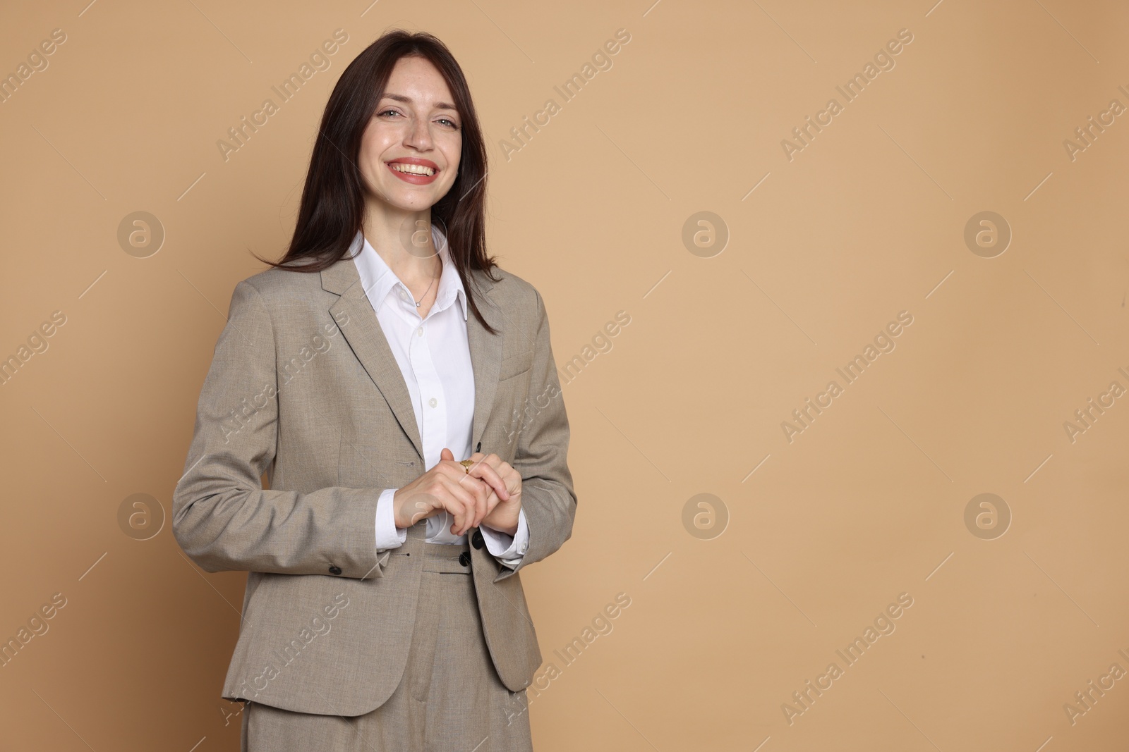 Photo of Happy woman in suit on beige background, space for text
