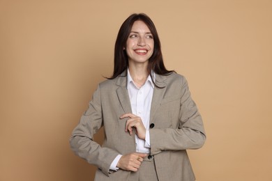 Photo of Happy woman in suit on beige background