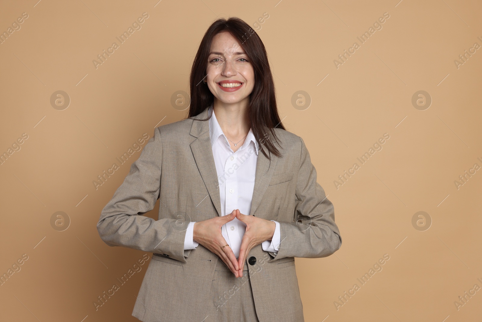 Photo of Happy woman in suit on beige background
