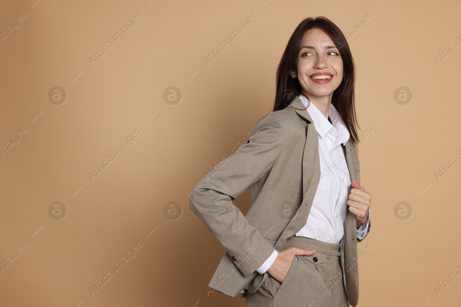 Photo of Happy woman in suit on beige background, space for text