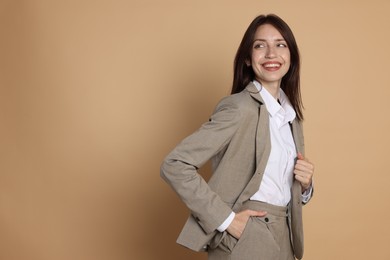 Photo of Happy woman in suit on beige background, space for text
