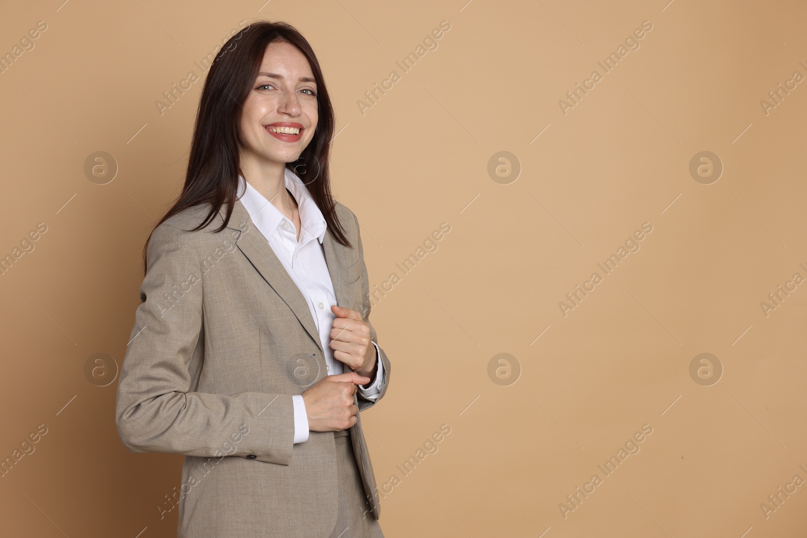 Photo of Happy woman in suit on beige background, space for text