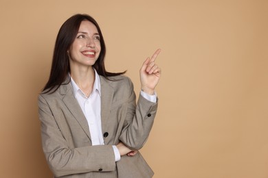 Photo of Happy woman in suit on beige background, space for text
