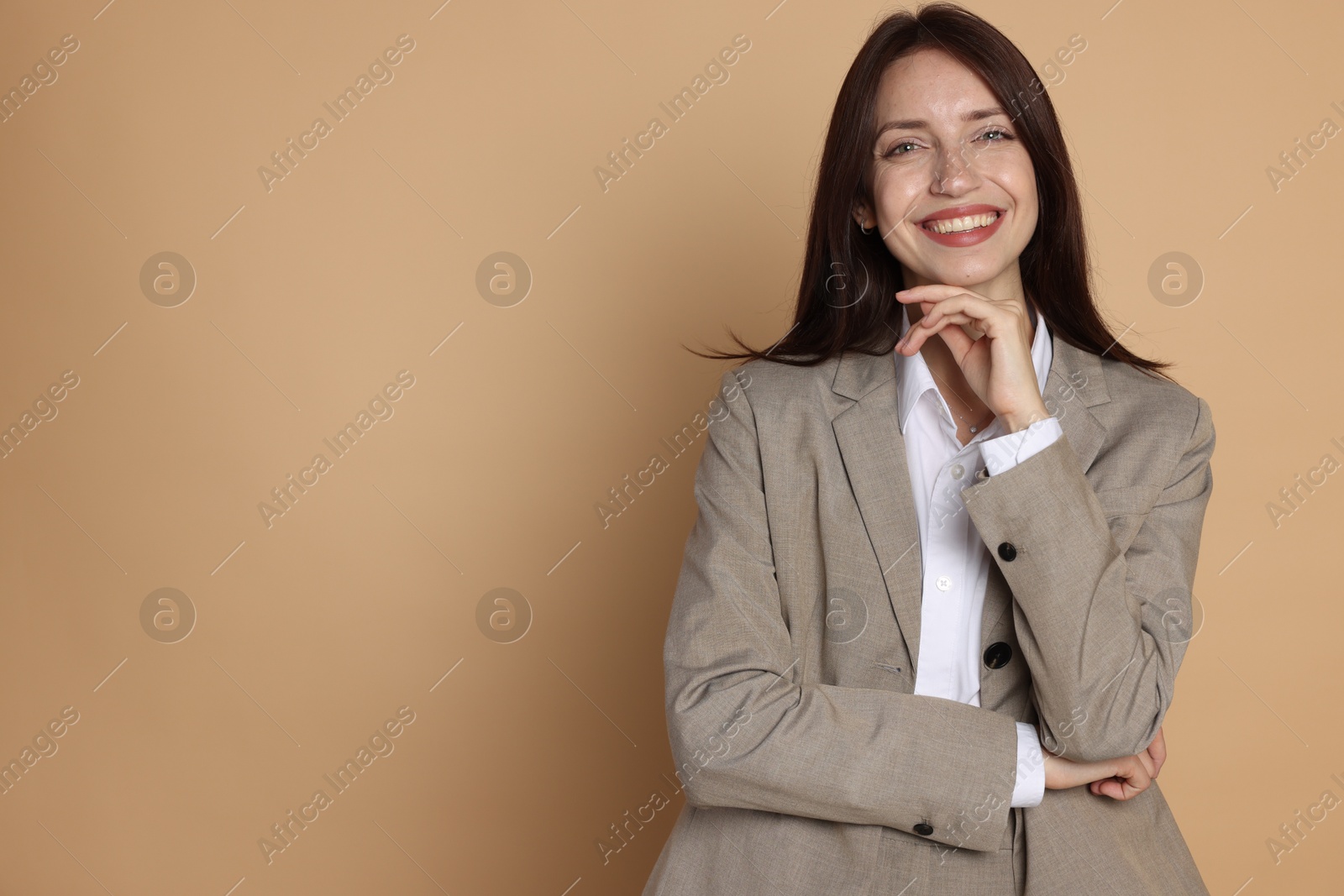 Photo of Happy woman in suit on beige background, space for text