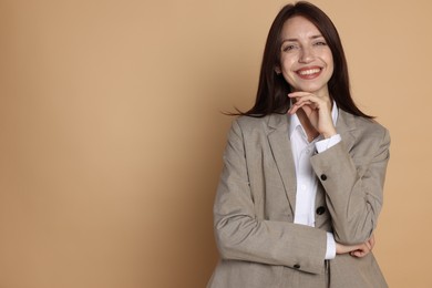 Photo of Happy woman in suit on beige background, space for text