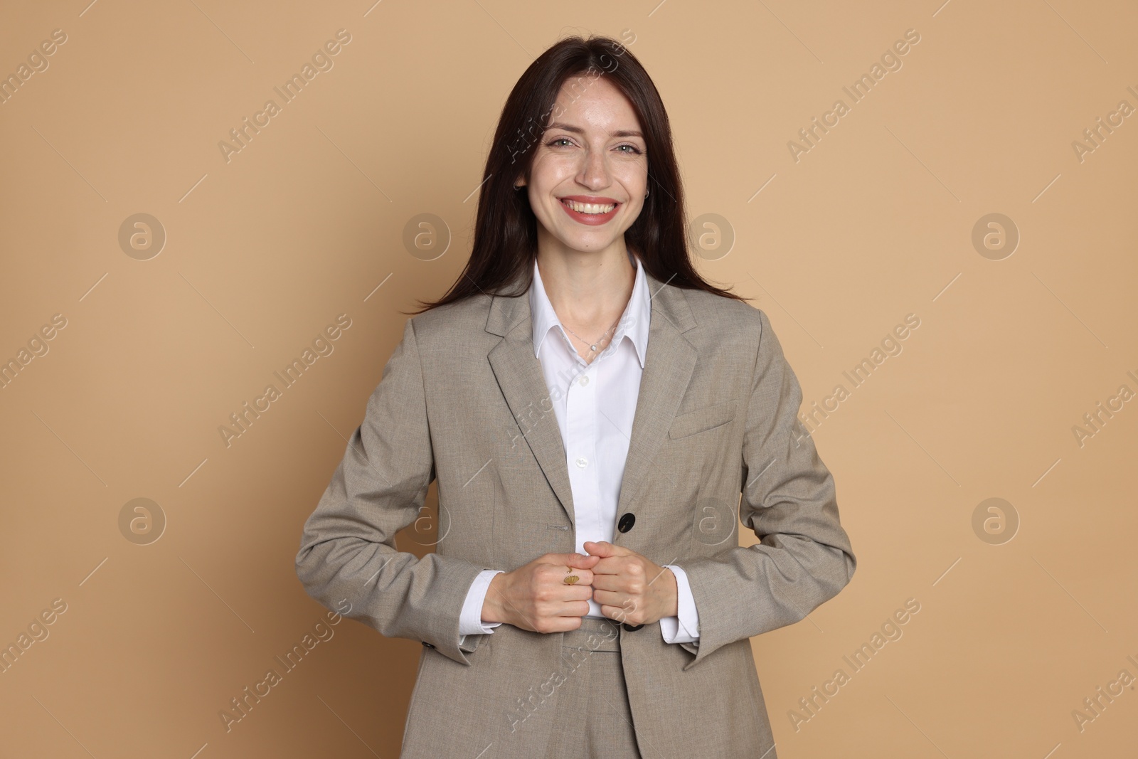 Photo of Happy woman in suit on beige background