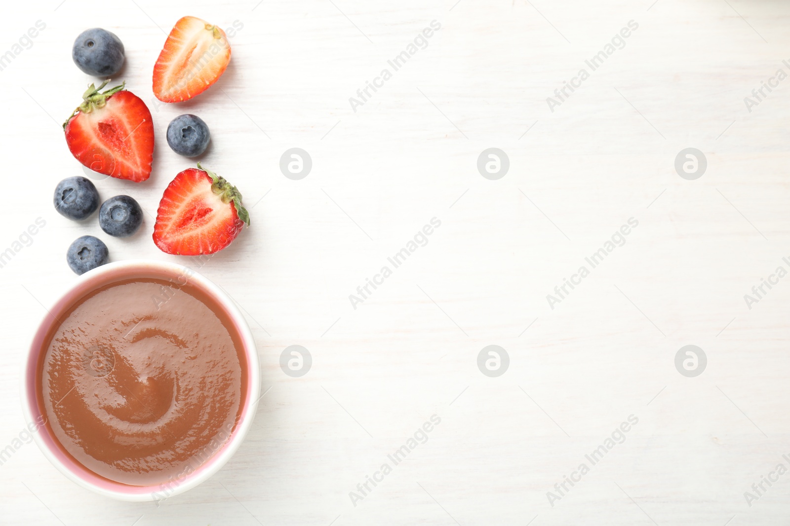 Baby food. Tasty puree in bowl and different ingredients on white wooden table, flat lay. Space for text Photo of Baby food. Tasty puree in bowl and different ingredients on white wooden table, flat lay. Space for text