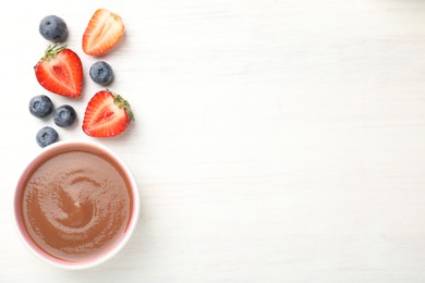 Photo of Baby food. Tasty puree in bowl and different ingredients on white wooden table, flat lay. Space for text