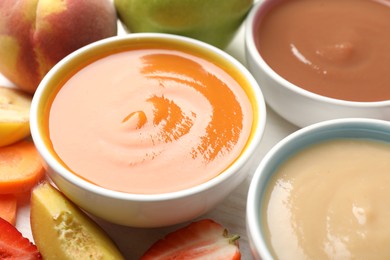Photo of Baby food. Tasty puree in bowls and different ingredients on table, closeup