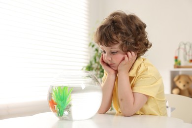 Photo of Little boy with goldfish in aquarium making wish at home. Space for text