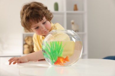Photo of Little boy with goldfish in aquarium on table at home