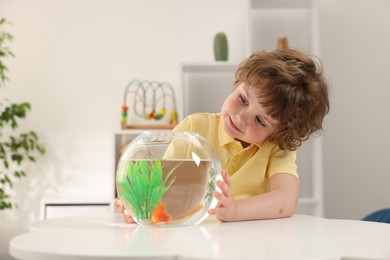 Photo of Little boy with goldfish in aquarium on table at home