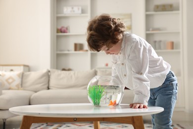 Photo of Little boy with goldfish in aquarium on table at home